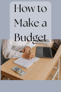 person writing in notebook with laptop and cash on table